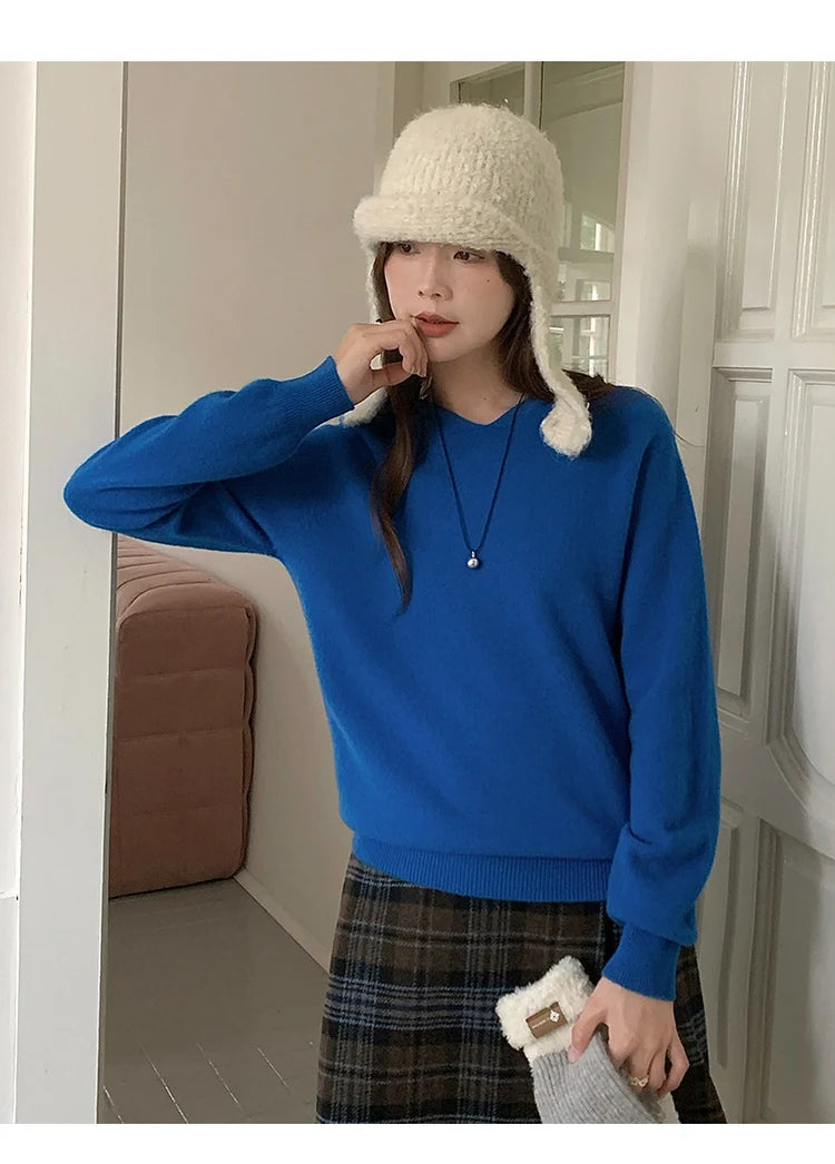 Blue:: Person wearing a blue sweater and white knit hat indoors