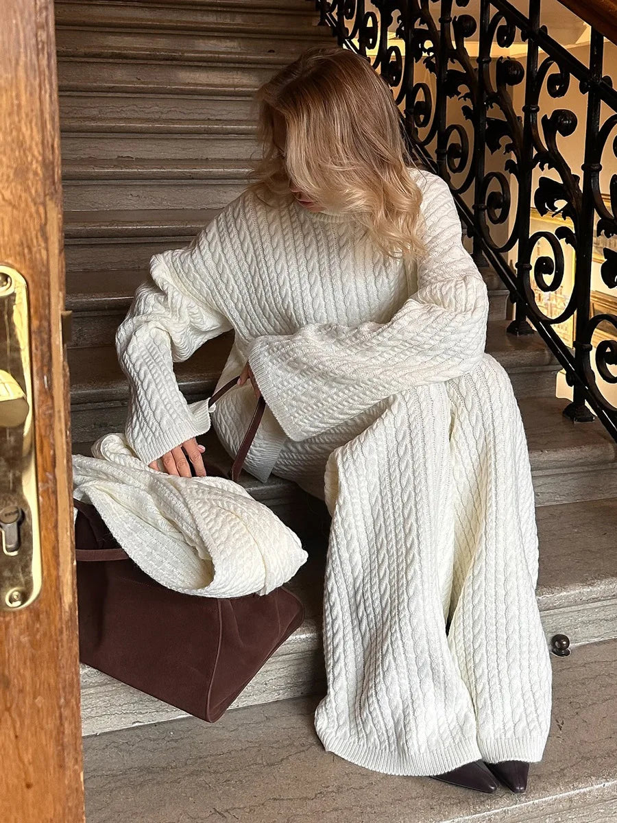 White:: Person wearing a white knitted outfit sitting on a staircase.