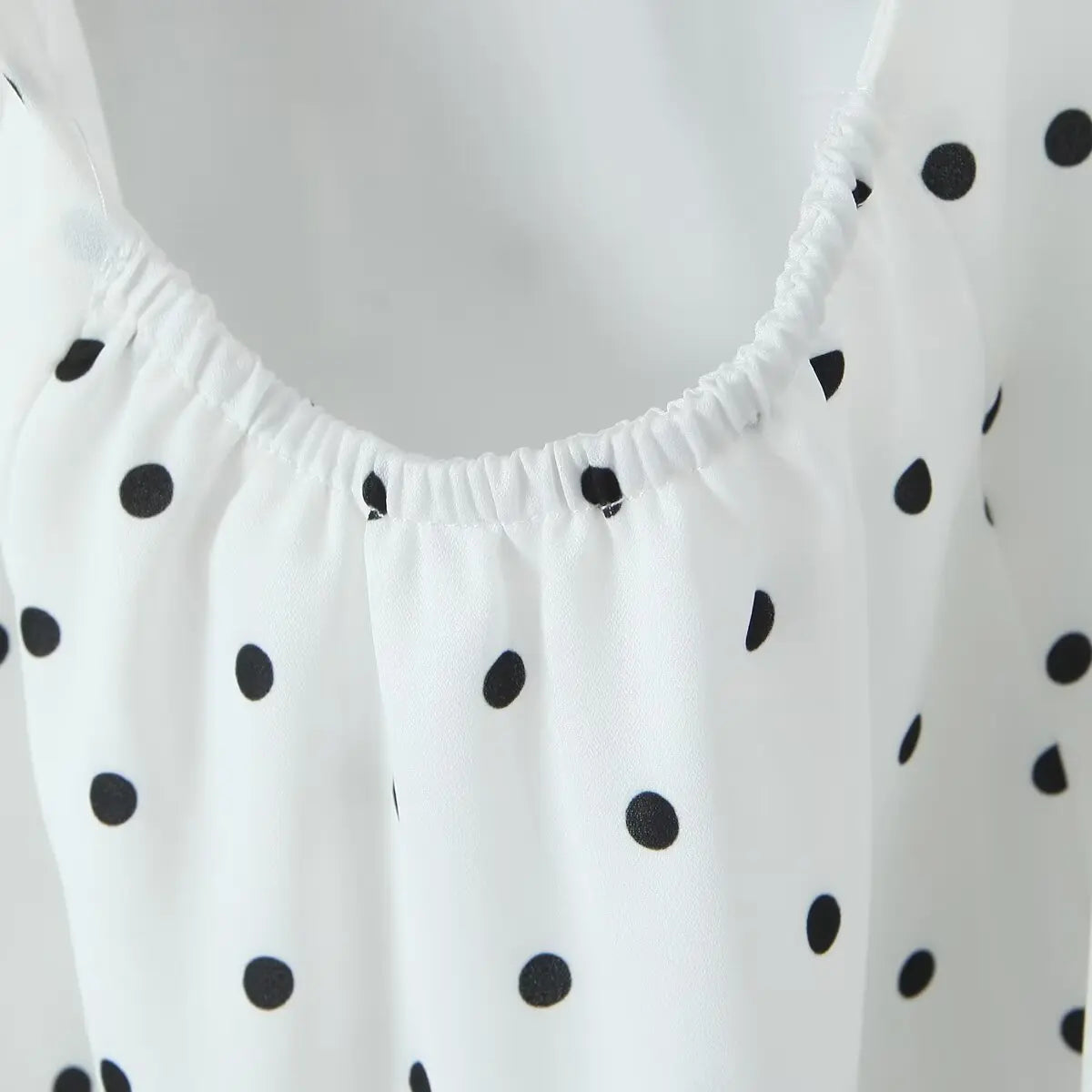 white::White top with black polka dot pattern on a plain background
