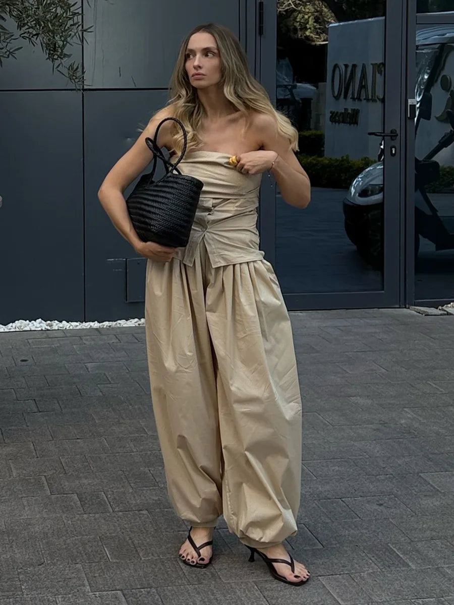 khaki::Woman in a beige outfit holding a black bag on a city street.