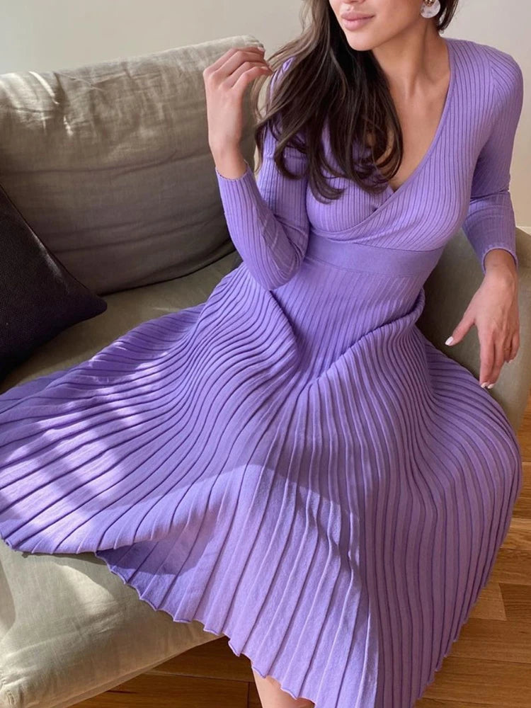 allvariants:: Woman wearing a purple ribbed dress sitting on a couch.