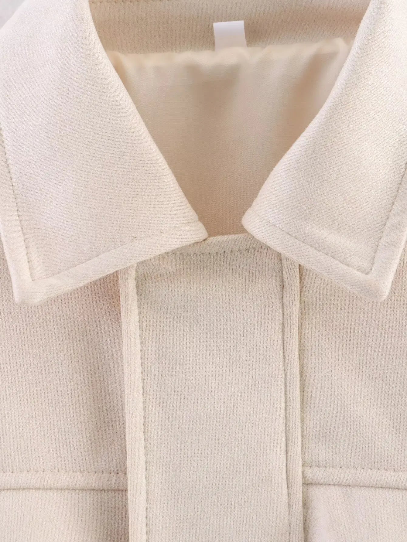 allvariant::Close-up of a beige coat with a collar and label.