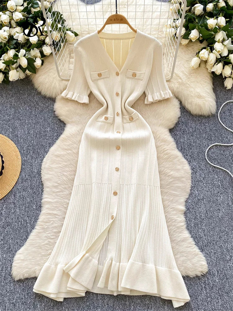 allvariants:: White dress with buttons on a hanger against a decorative background with flowers and fur.