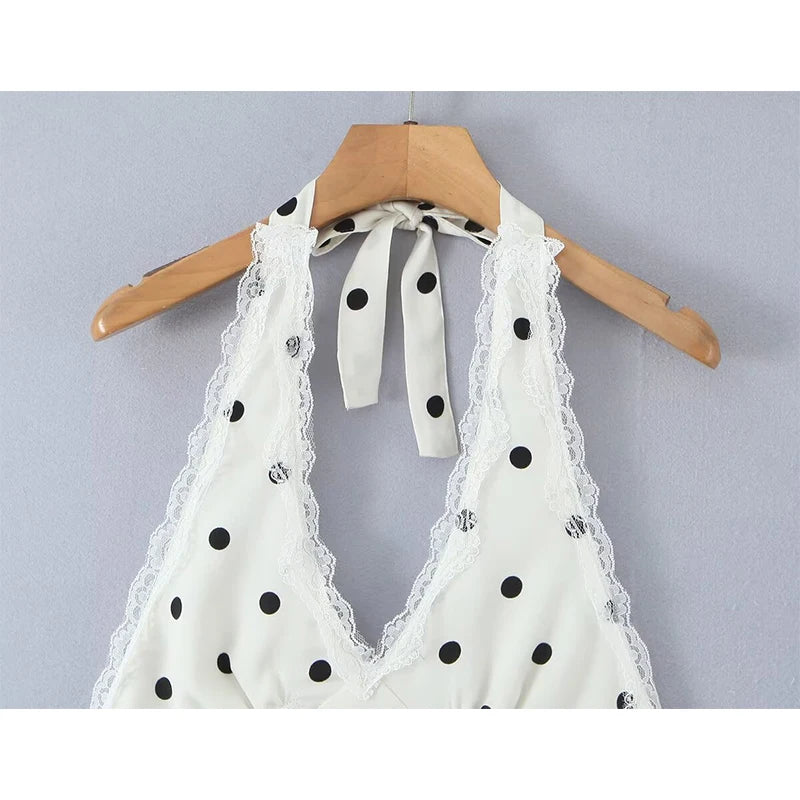 white::White lace halter top with black polka dots on a wooden hanger against a light gray background