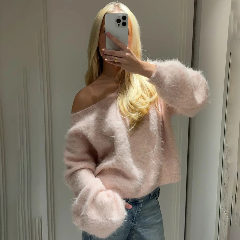 pink::Person wearing a pink off-shoulder sweater and blue jeans taking a mirror selfie.