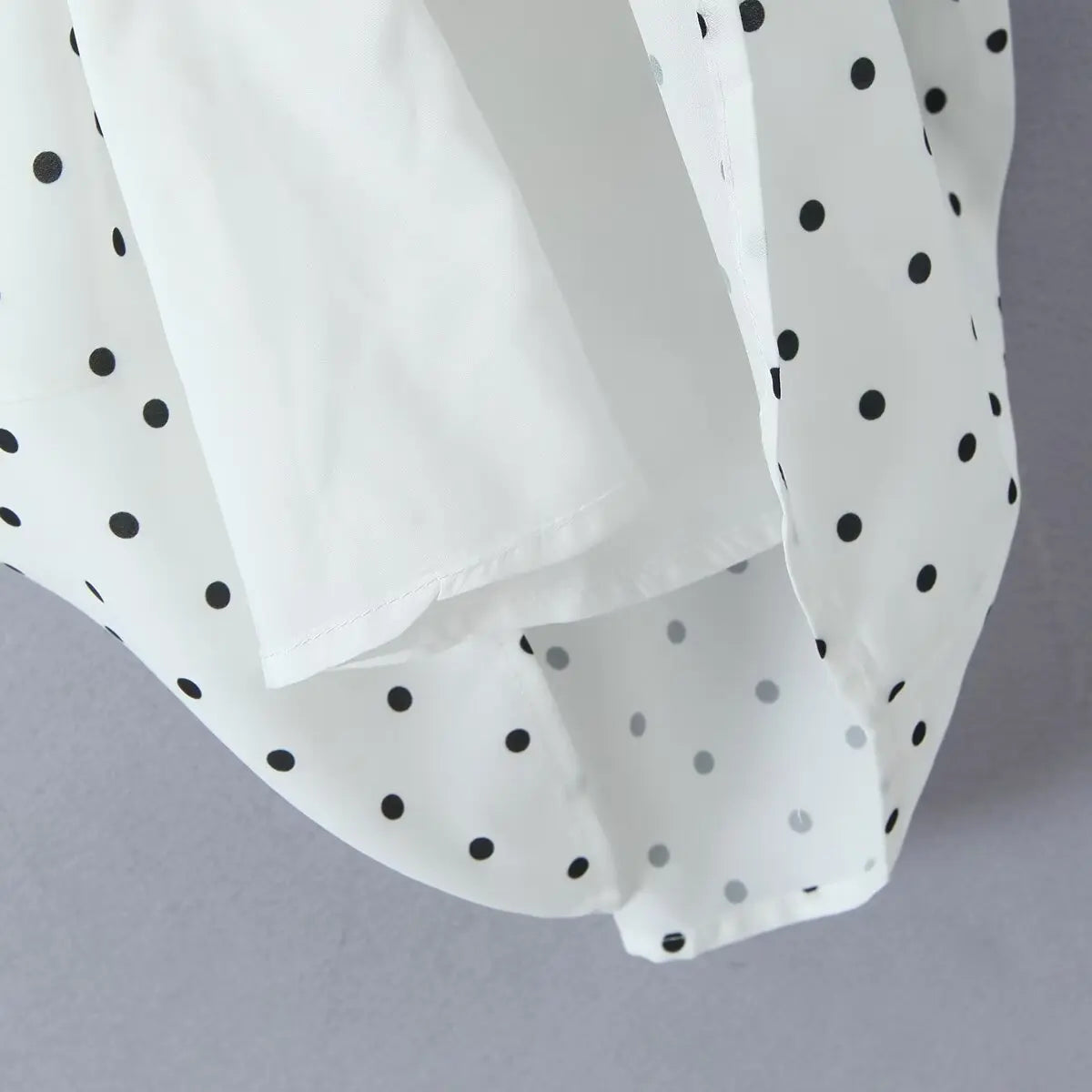 white::White fabric with black polka dots on a gray background