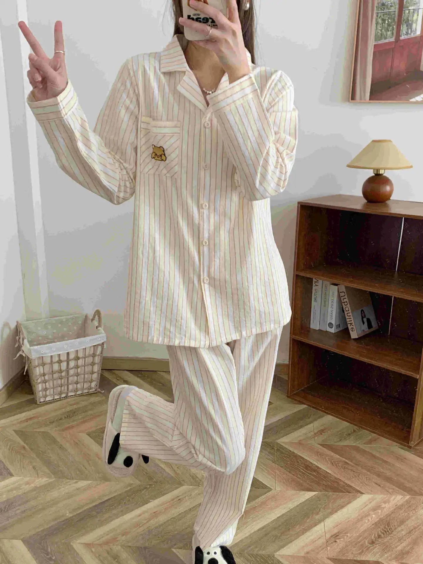 01:: Person wearing a striped pajama set in a room with a wooden shelf and lamp.