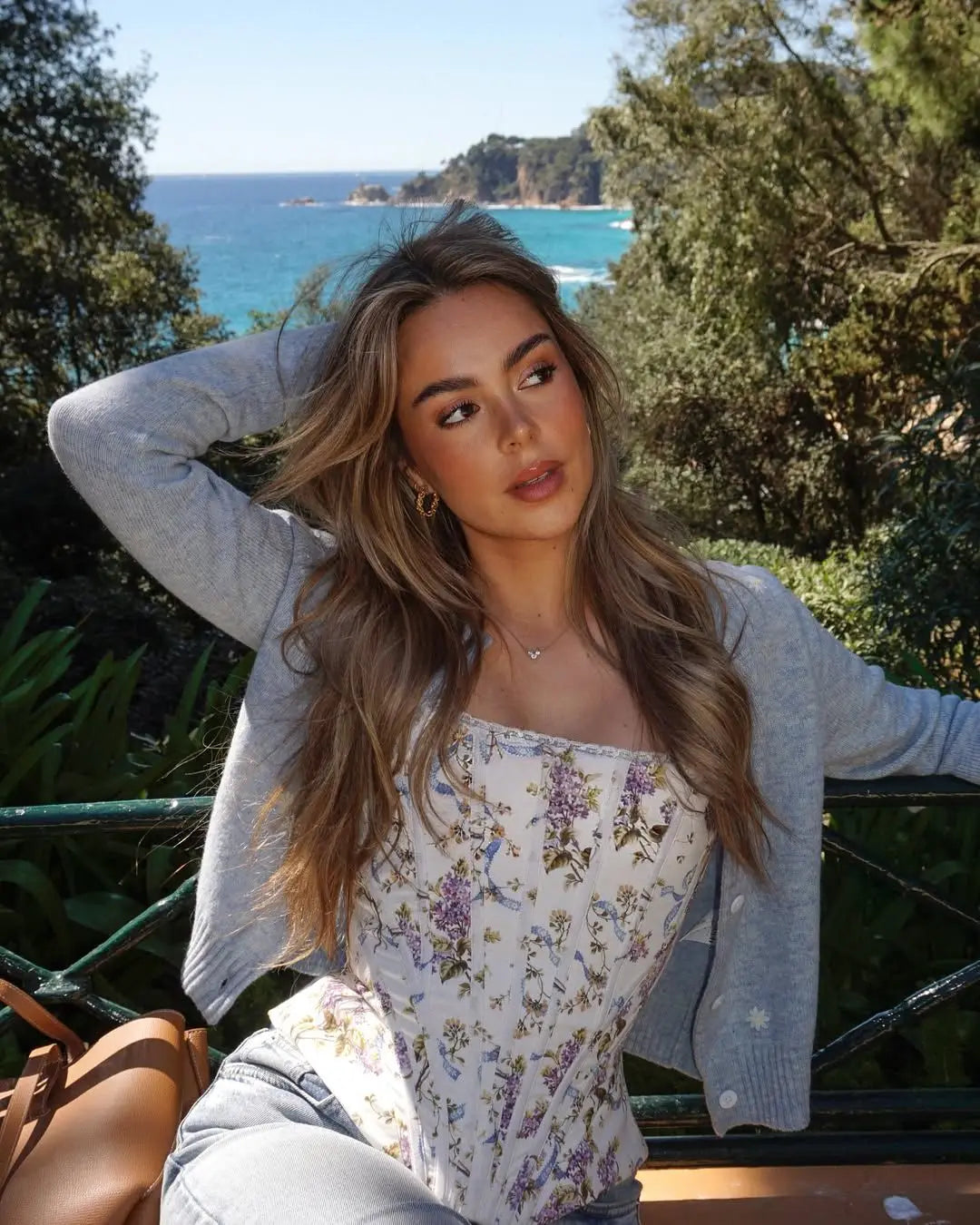 cream::Woman sitting outdoors with ocean and trees in the background