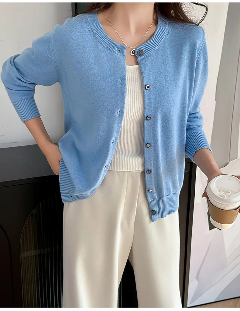 Blue:: Person wearing a blue cardigan over a white top, holding a coffee cup.