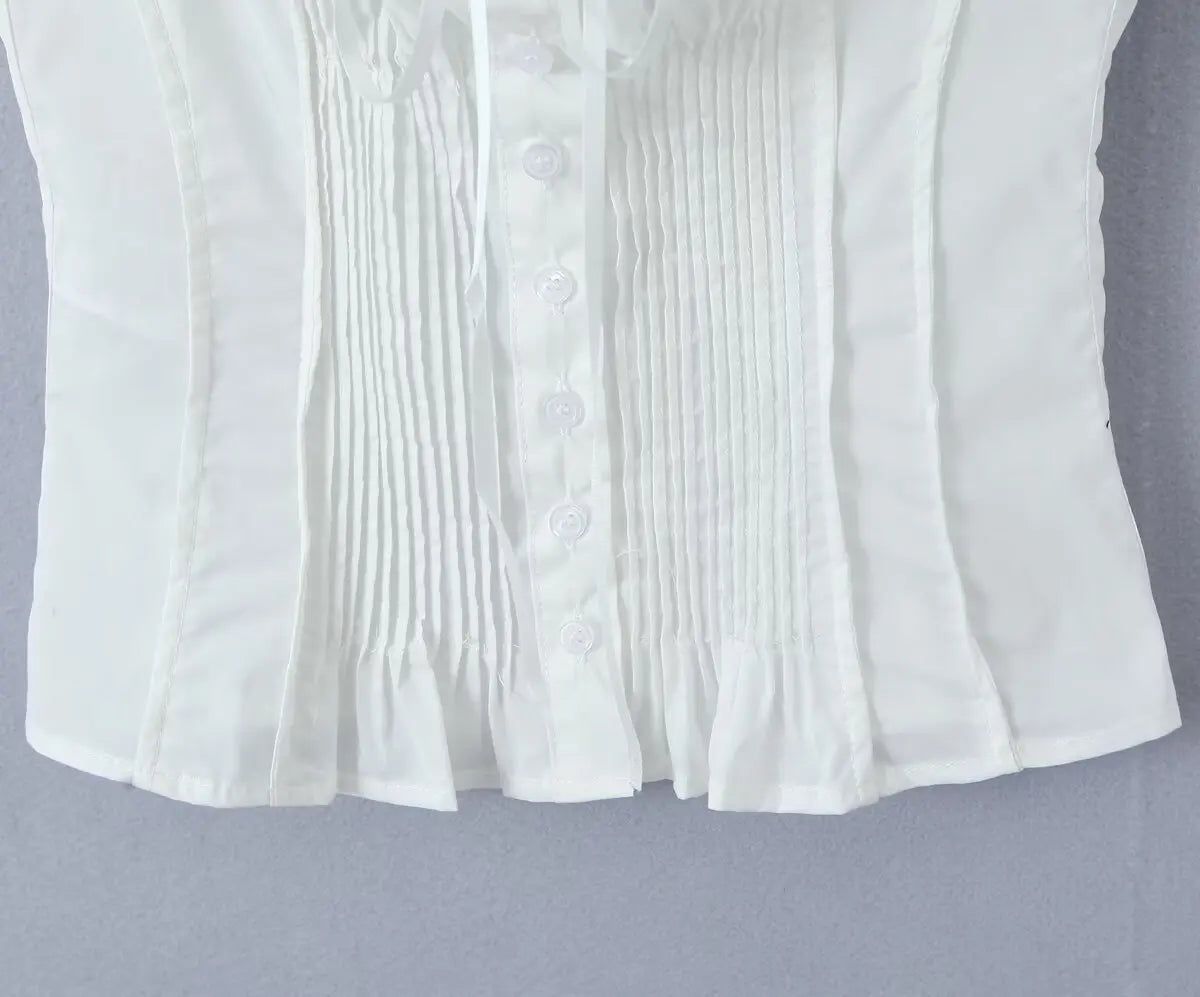 white::White pleated blouse with button details on a gray background