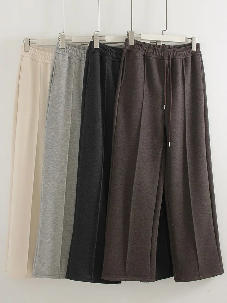 allvariants:: Four pairs of wide-leg pants in beige, gray, black, and brown hanging on a rack against a white background.