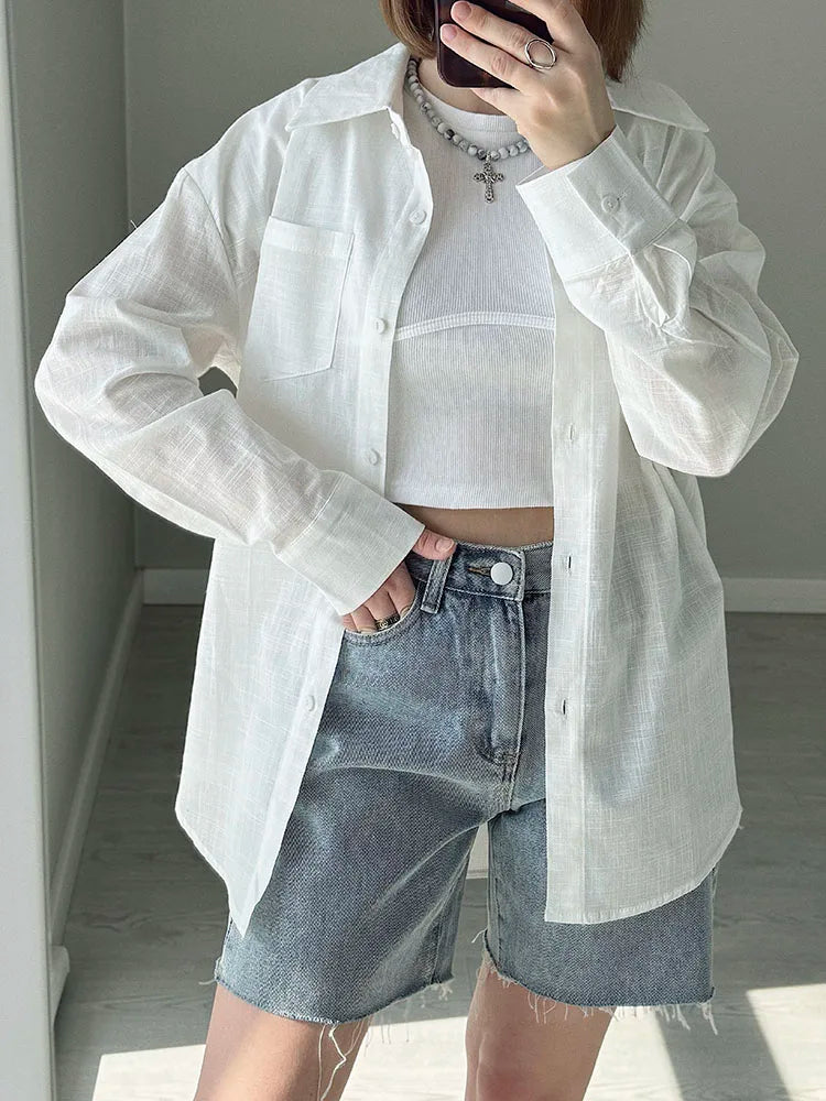 allvariants:: Person wearing a white sheer shirt over a white top with denim shorts indoors.