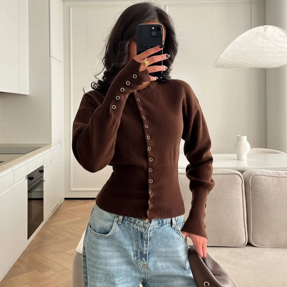 brown::Person wearing a brown cardigan and blue jeans taking a mirror selfie in a modern kitchen.