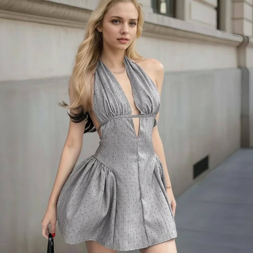 as picture:: Woman wearing a gray halter dress with cut-out design in an urban setting.