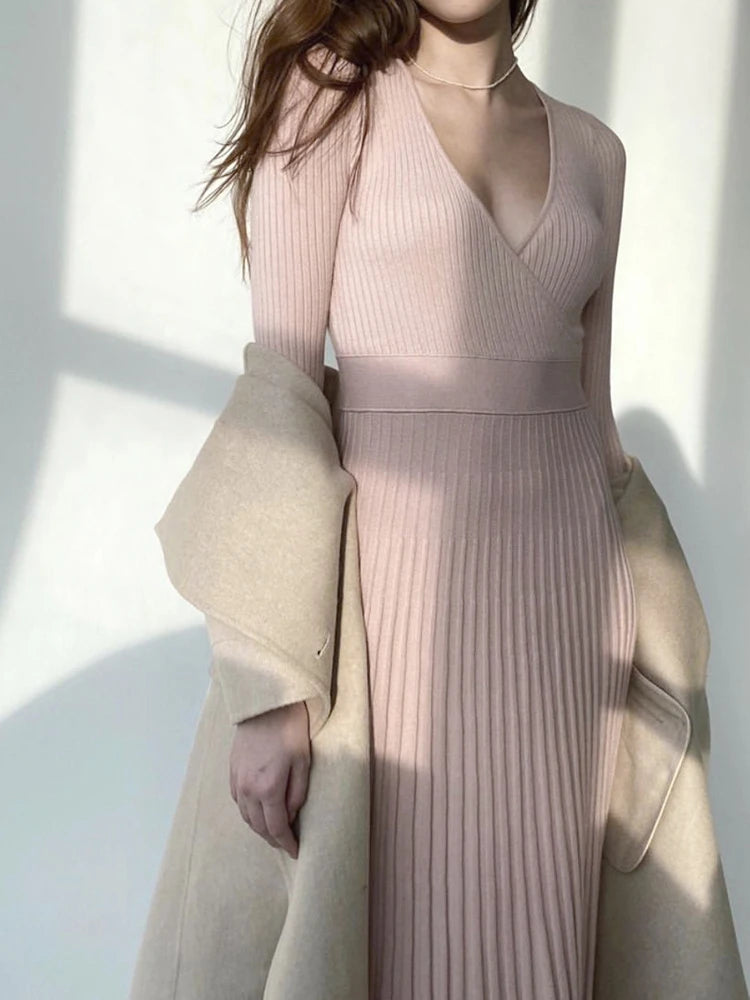 allvariants:: Woman wearing a pink ribbed dress with a beige coat against a white background