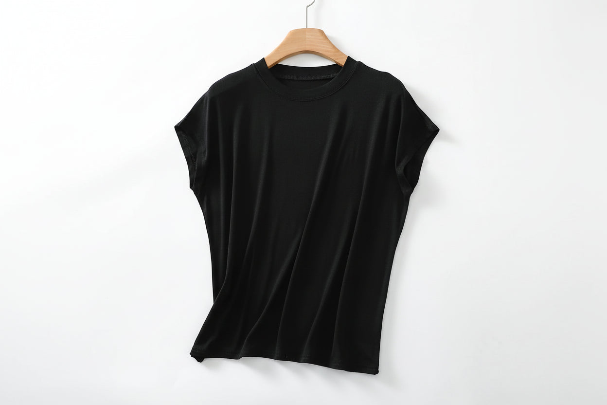 allvariants:: Black sleeveless top on a wooden hanger with a magazine and a bowl of berries in the background.