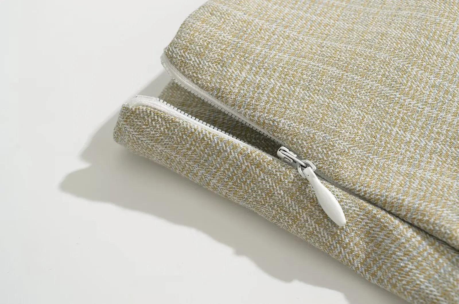 allvariant::Close-up of a textured fabric pouch with a zipper on a light background