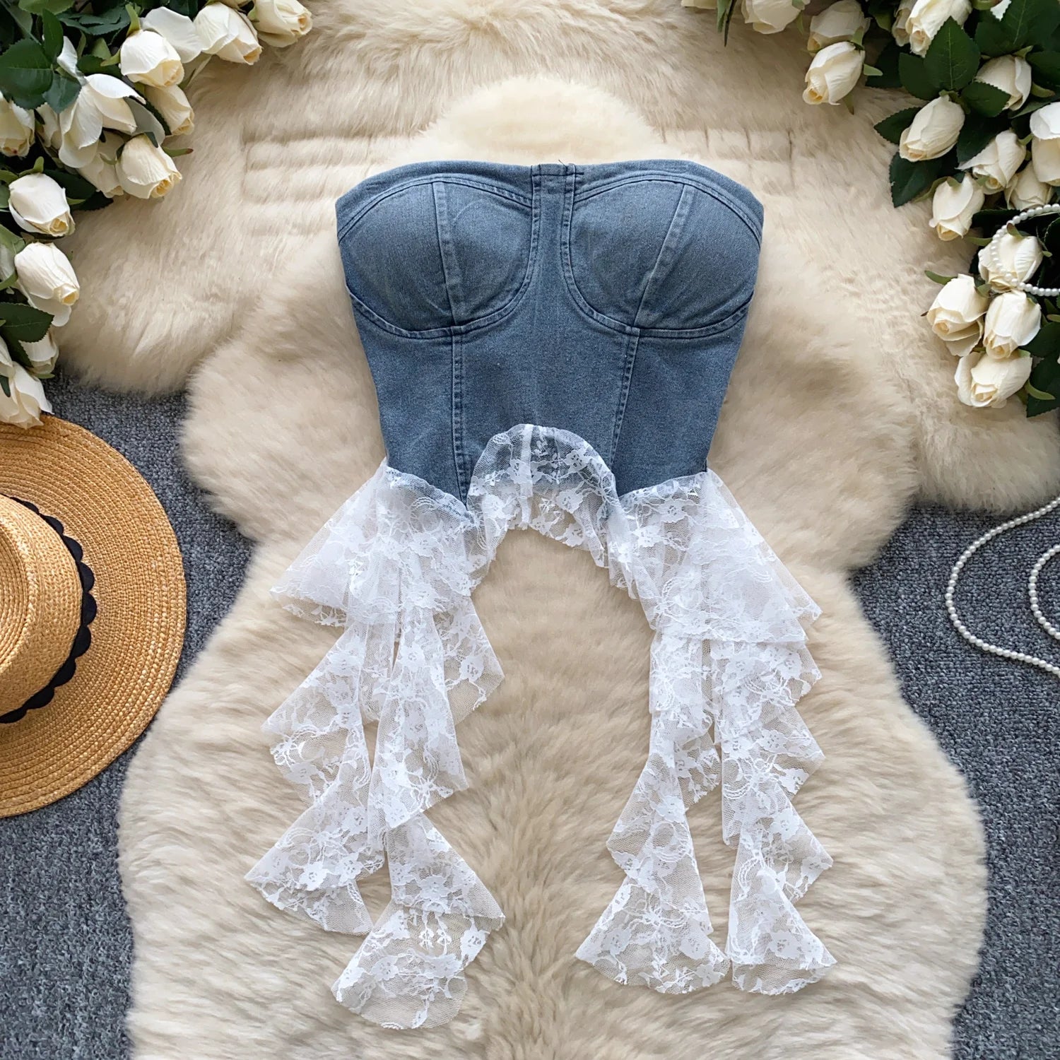 allvariants:: Denim strapless top with lace overlay on a fluffy white surface surrounded by flowers and a hat.