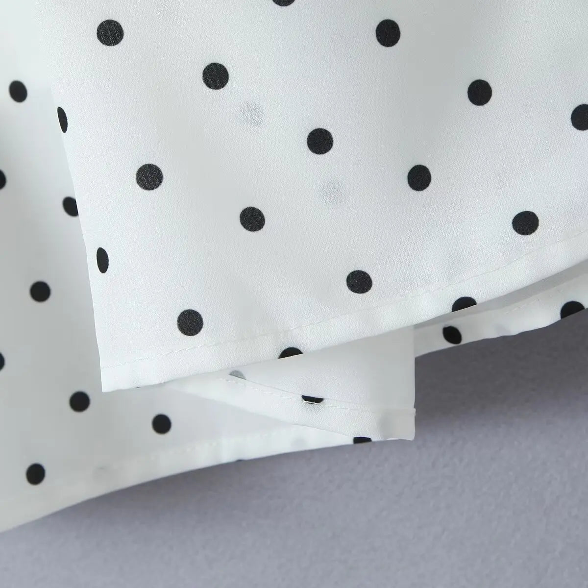 white::White fabric with black polka dots on a gray background