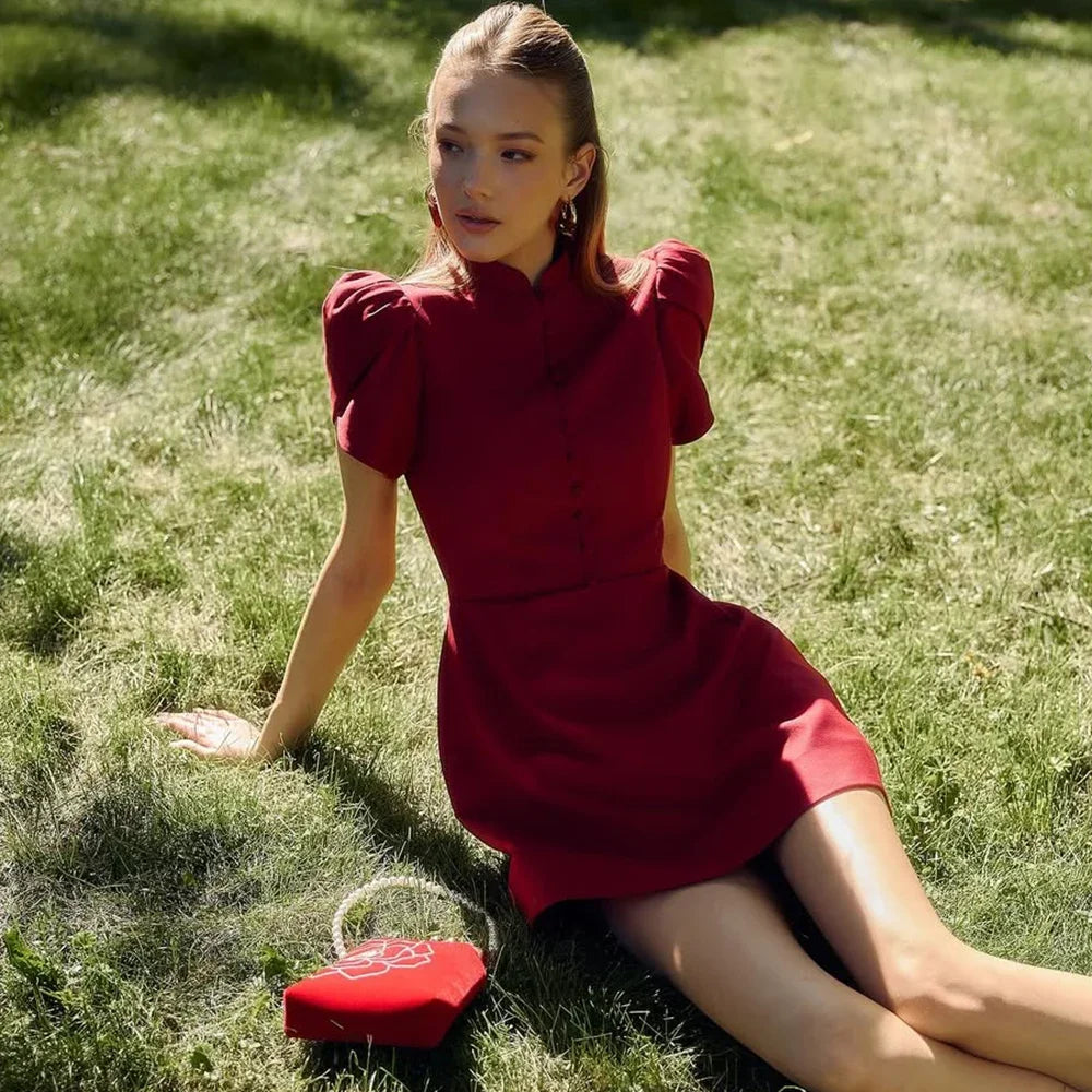 allvariants:: Woman in a red dress sitting on grass with a red bag beside her