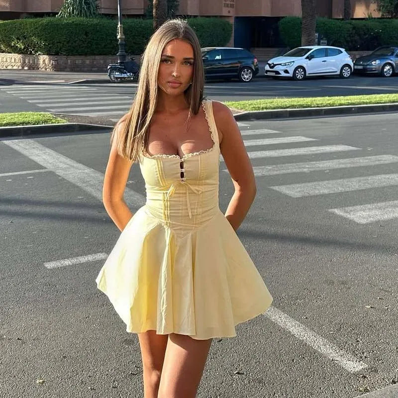 yellow:: Woman in a yellow dress standing on a street corner with cars in the background