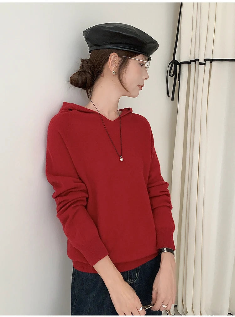 Person wearing a red hoodie and black cap against a neutral background