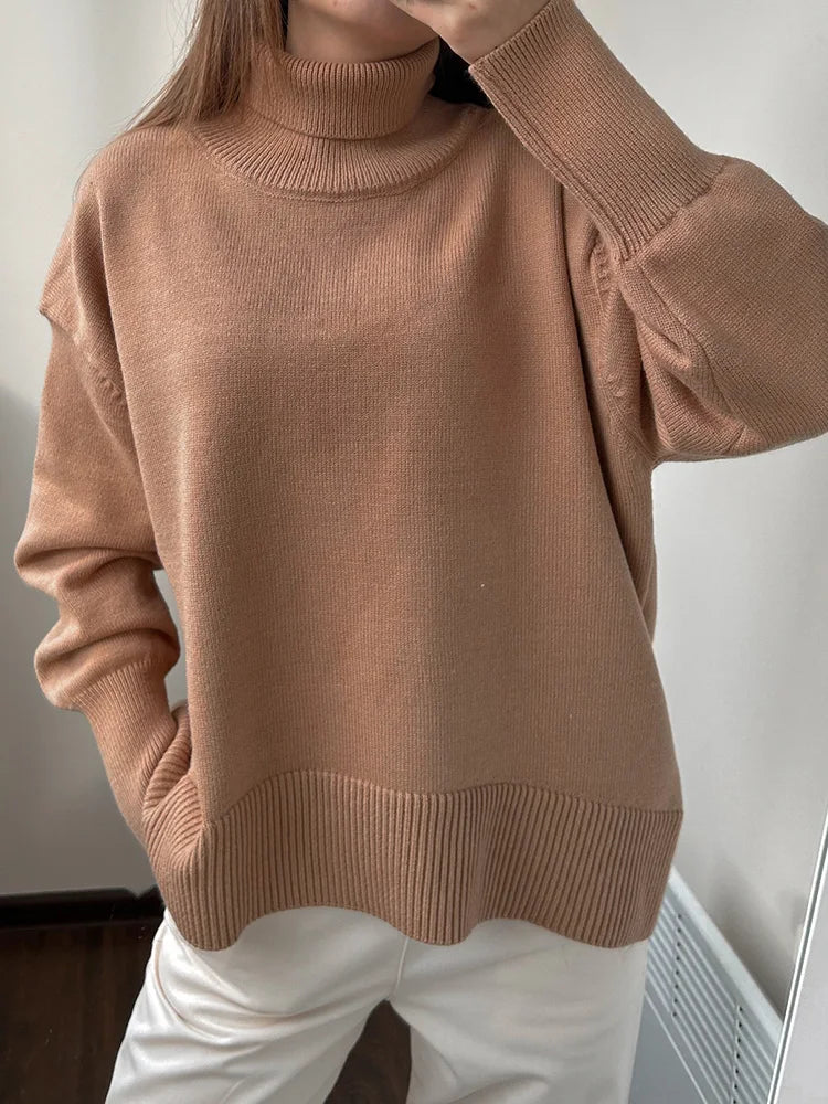 allvariants:: Person wearing a brown turtleneck sweater and white pants against a plain background