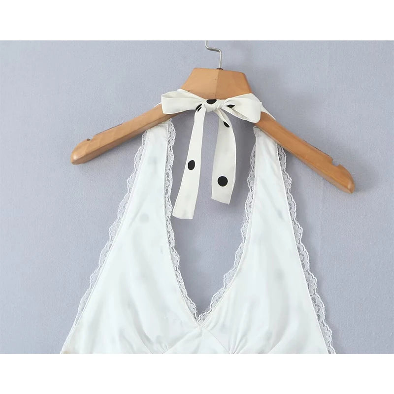 white::White lace top with black polka dots on a wooden hanger against a gray background