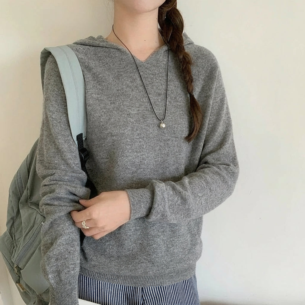 light grey:: Person wearing a gray hoodie with a backpack, holding a phone, on a plain background.