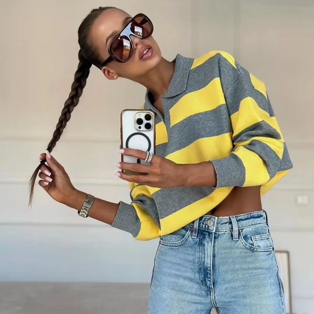 stripped::Person wearing a yellow and gray striped sweater and blue jeans, taking a selfie.
