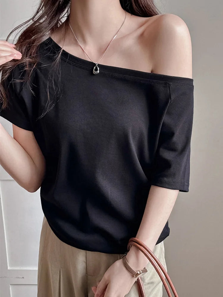 allvariants:: Person wearing a black off-shoulder top with beige pants against a neutral background