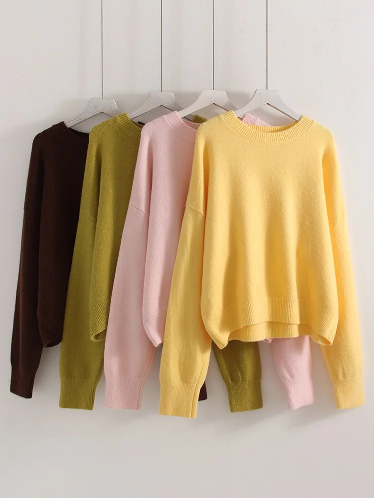 allvariants:: Five sweaters in different colors hanging on a rack against a white wall.
