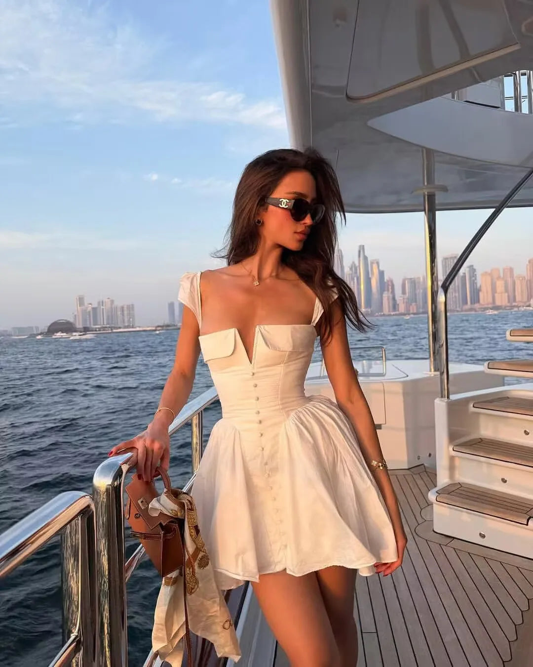 White:: Woman in a white dress on a boat with a city skyline in the background