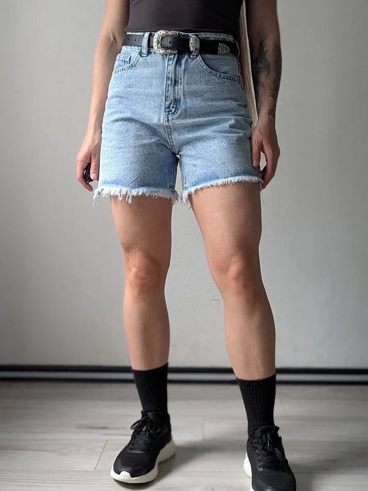 Light Blue:: Person wearing light blue denim shorts with a plain background