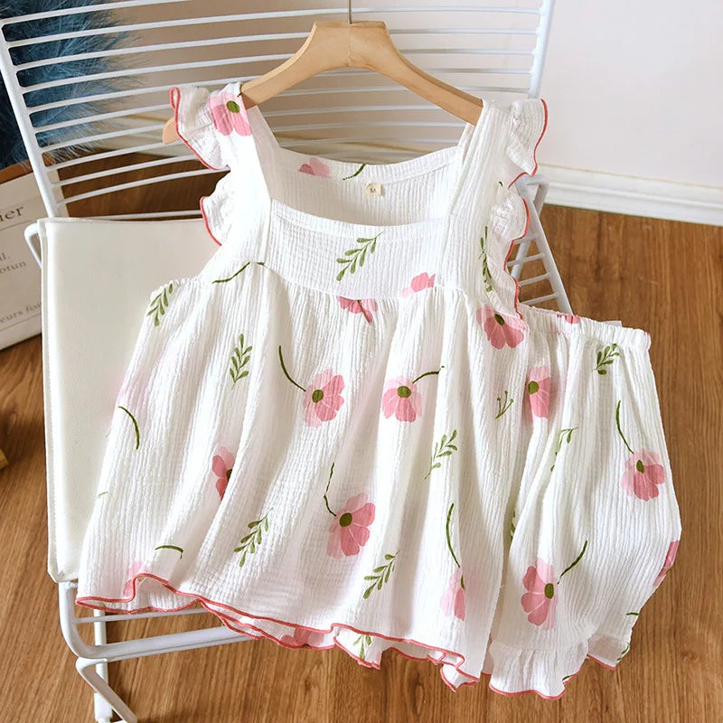 allvariants:: White baby dress with pink floral pattern on a hanger against a white chair.
