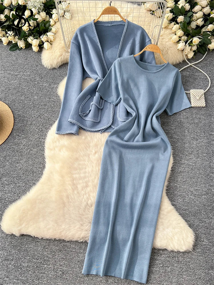 allvariants:: Light blue dress and cardigan set on a textured surface with decorative elements.