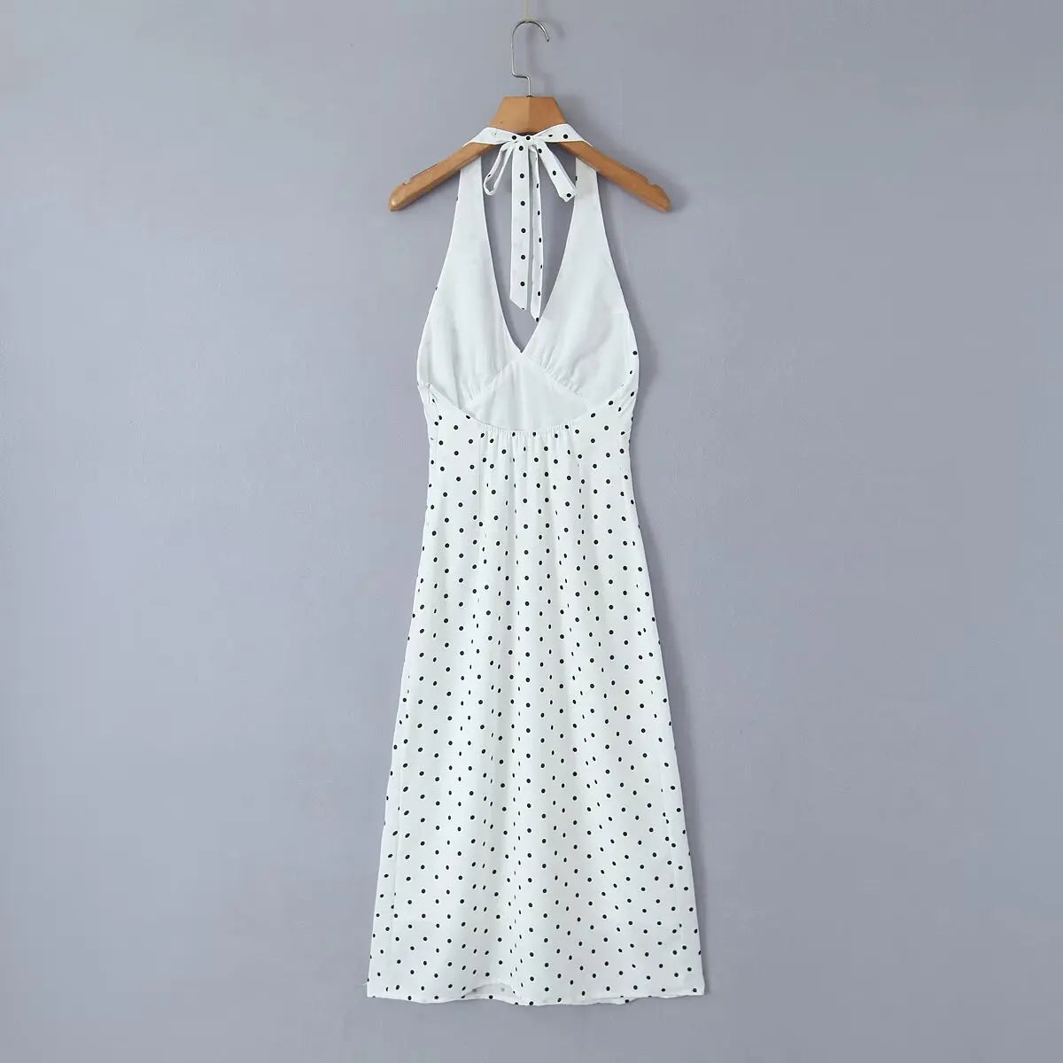 white::White dress with black polka dots on a hanger against a gray background