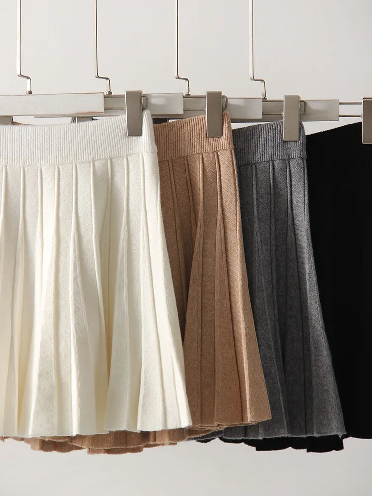allvariants:: Four skirts in white, brown, gray, and black hanging on a rack against a white background.