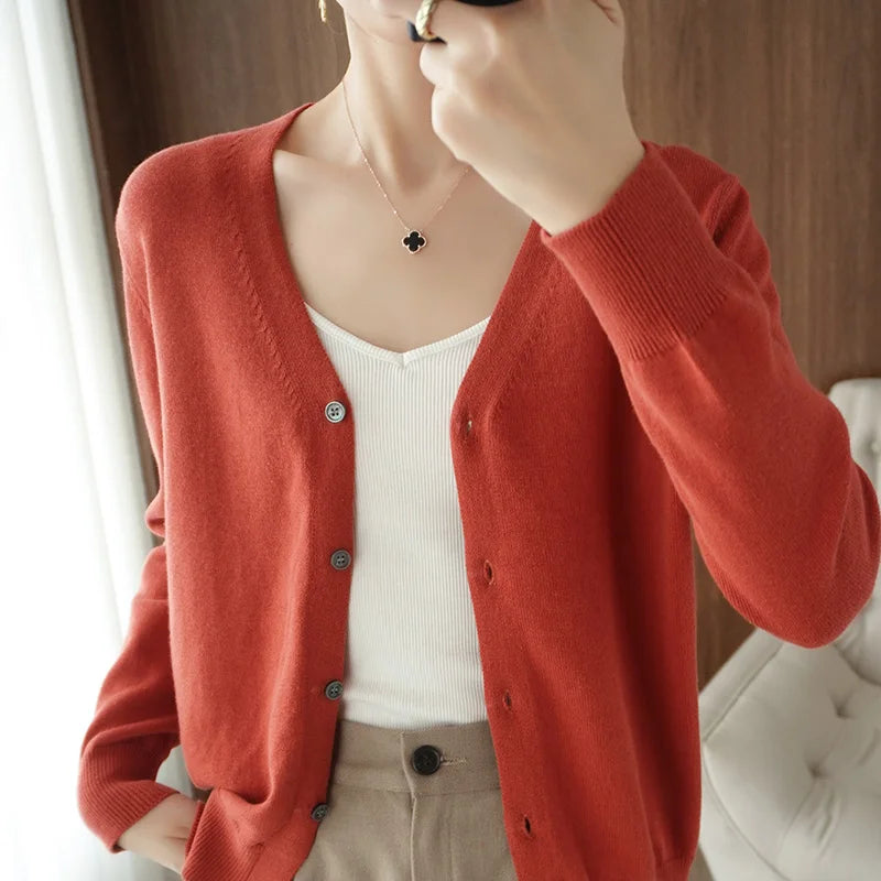 allvariants:: Person wearing a red cardigan over a white top and beige pants, with a blurred background.