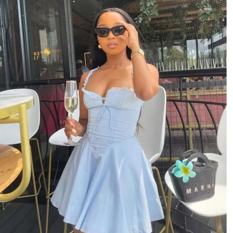 blue::Woman in a light blue dress holding a glass of champagne outdoors.
