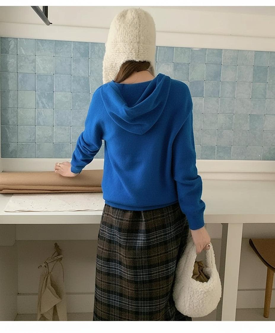 Blue:: Person wearing a blue hoodie and plaid skirt in a kitchen setting