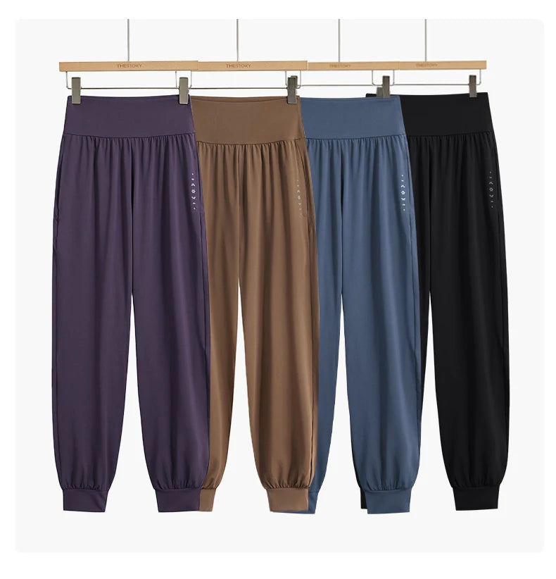 allvariants:: Four pairs of jogger pants in different colors hanging on a rack against a white background.