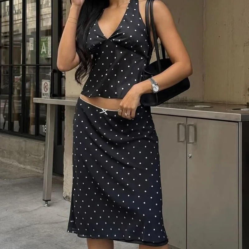 black::Woman wearing a black polka dot dress standing outdoors.