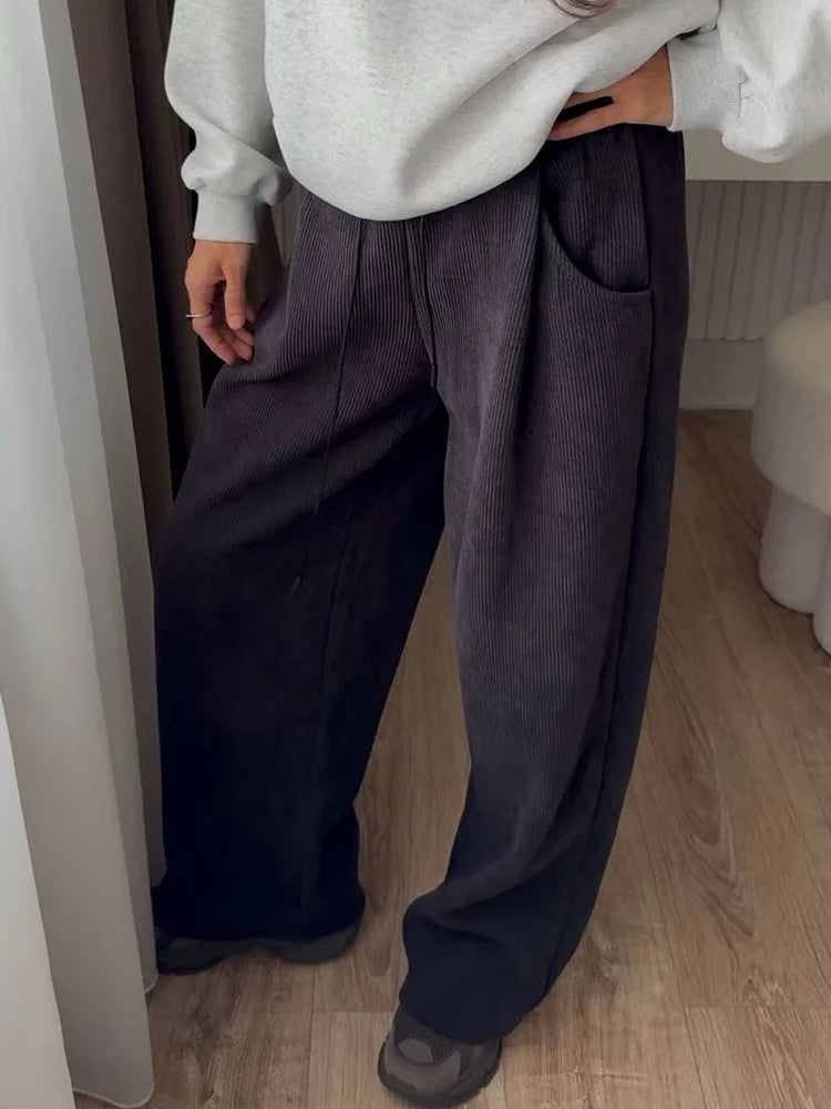 allvariants:: Person wearing a white sweater and dark wide-leg pants indoors.