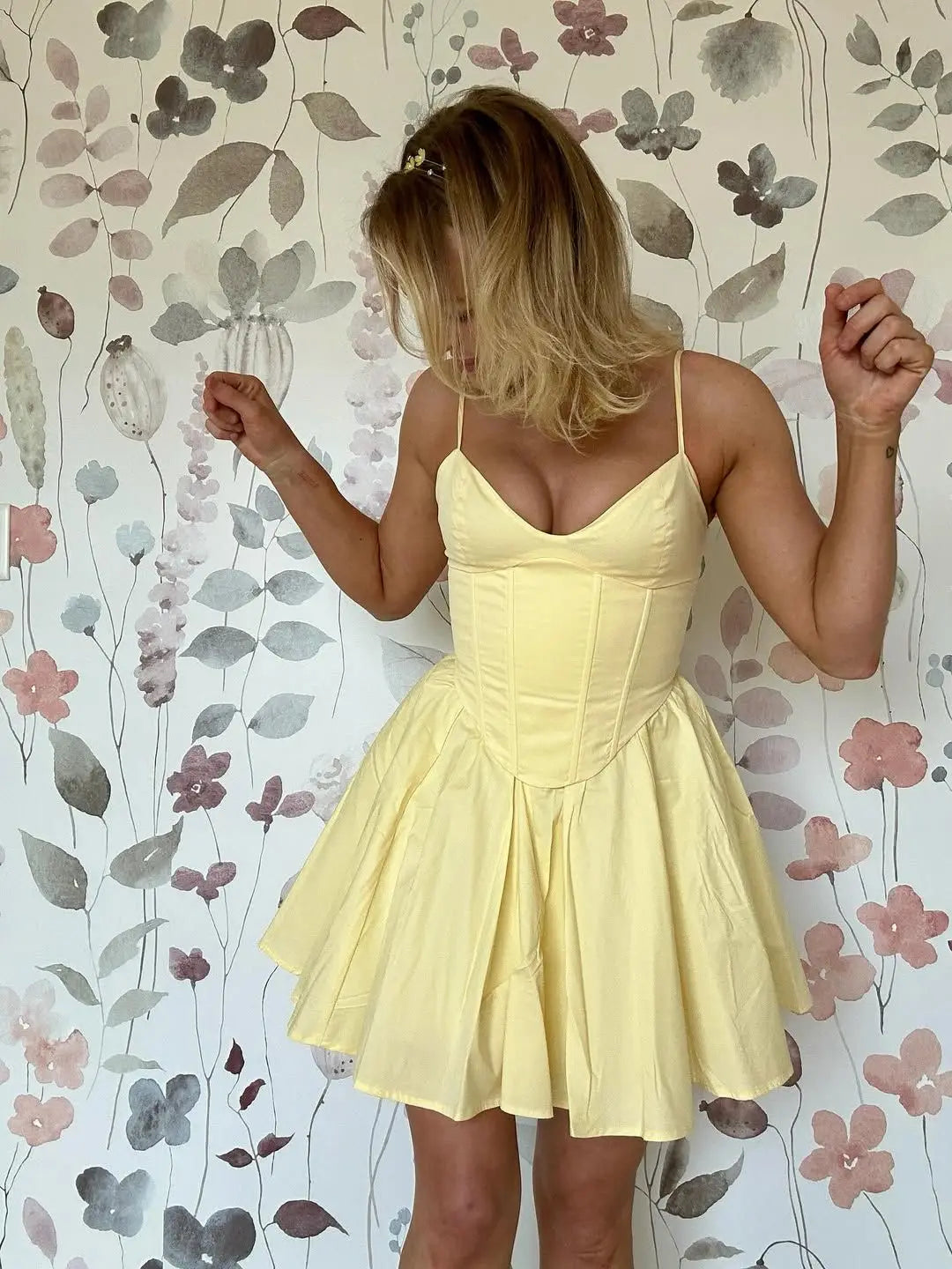 allvariant::Woman wearing a yellow dress against a floral wallpaper background