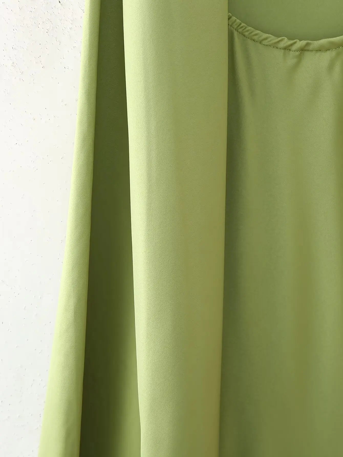 Green::Close-up of a green dress with a plain background