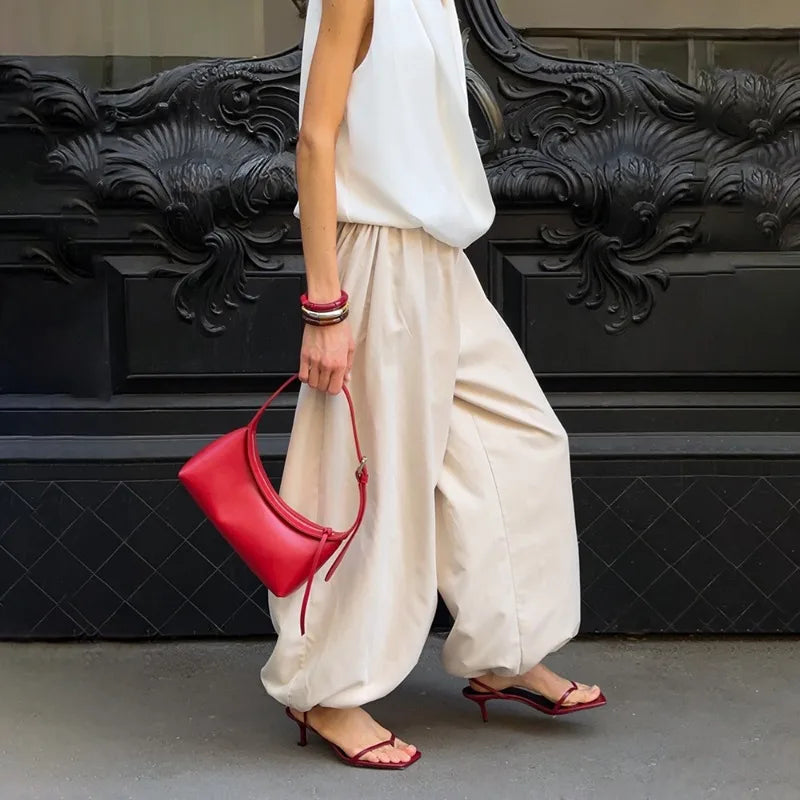 apricot::Person holding a red handbag in front of a black decorative wall.
