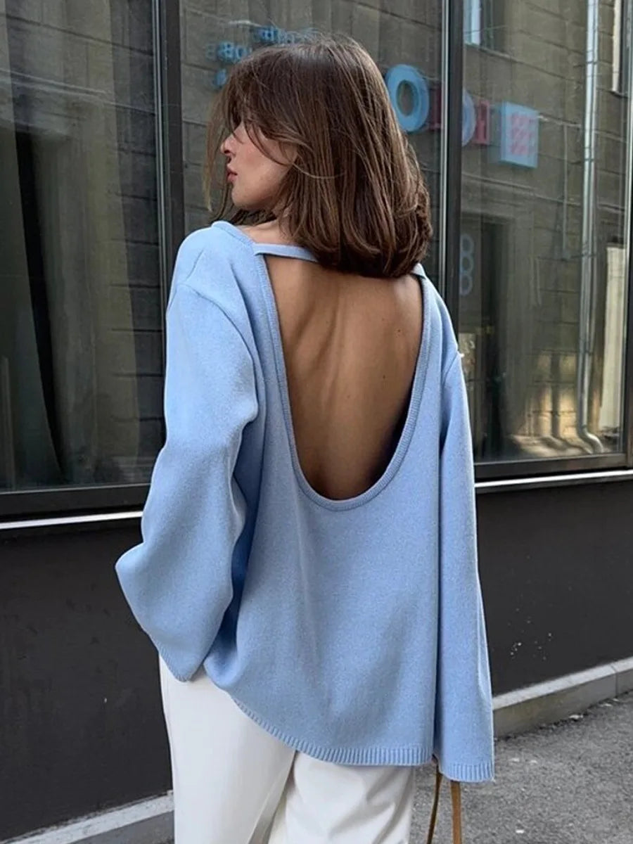allvariants:: Woman wearing a light blue open-back sweater in an urban setting