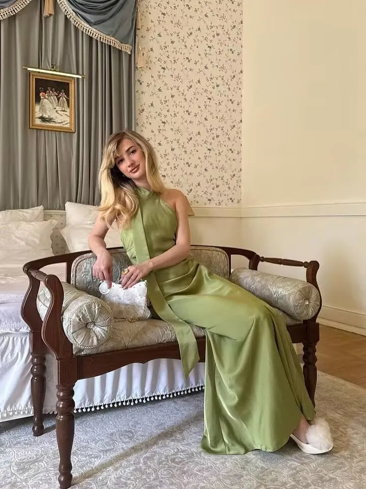 Green::Woman in a green dress sitting on a wooden bench in an elegant room.