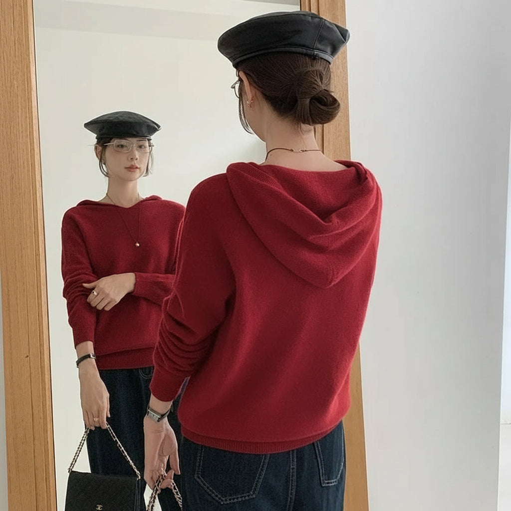 Red:: Person wearing a red hoodie and black cap looking at their reflection in a mirror.